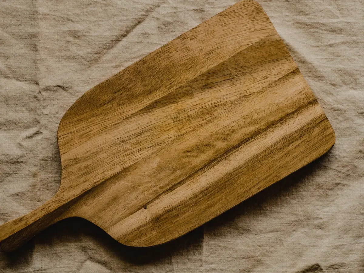 A wooden chopping board with a carved handle
